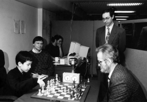 Andrew Whiteley playing a challenge match against 9-year-old David Howell in the year 2000. I am in the picture too as I was scoring the game. Looking on is Barry Gale, organiser of the Kensington tournaments at the time, and Alexis Harakis is at the computer analysing the game on Fritz. 